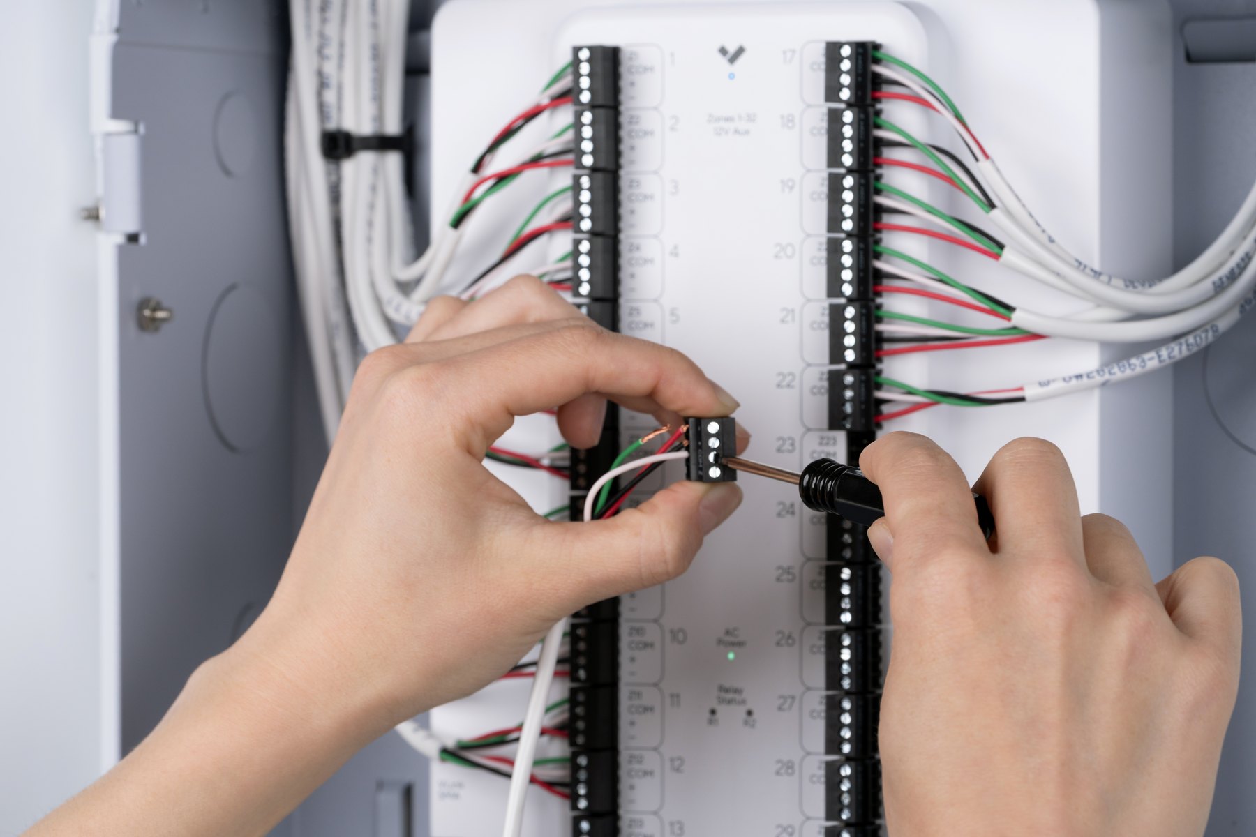 An engineer wiring an alarm panel